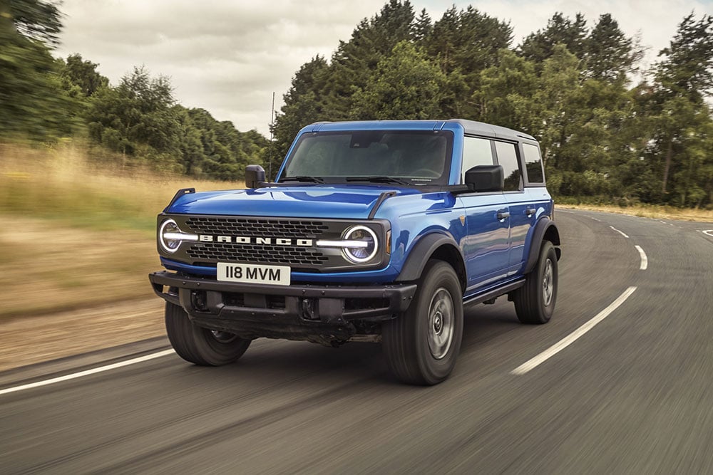 Vorderansicht des neuen Ford Bronco in Blau beim Fahren auf dem Land.