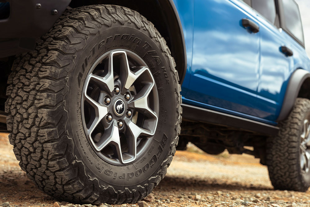 Eine Nahaufnahme der Geländereifen eines blauen Ford Bronco.