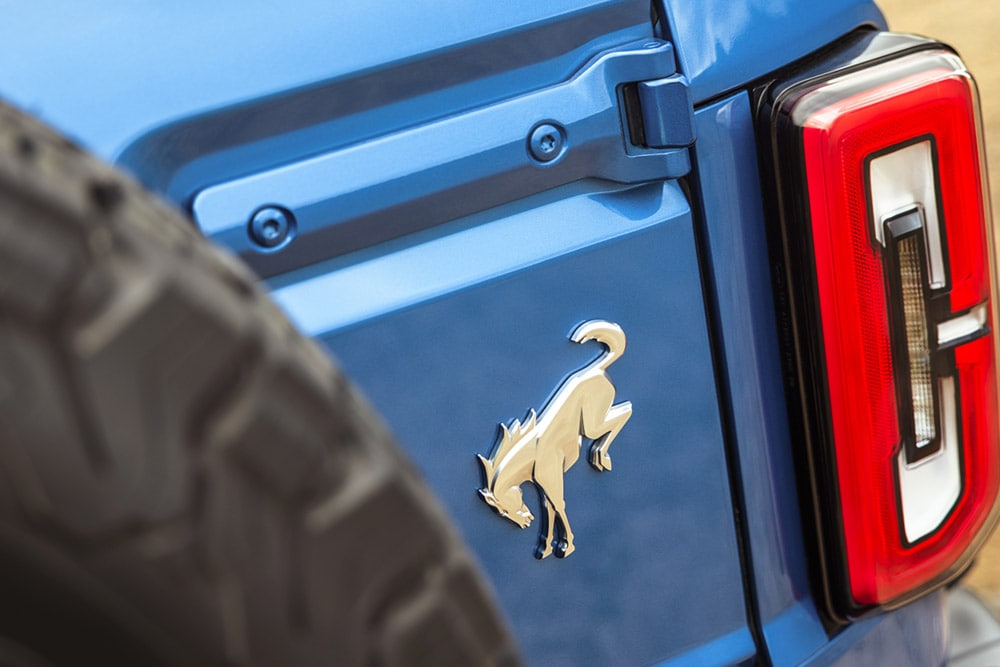 Eine Nahaufnahme der Markendetails auf der Rückseite eines blauen Ford Bronco.