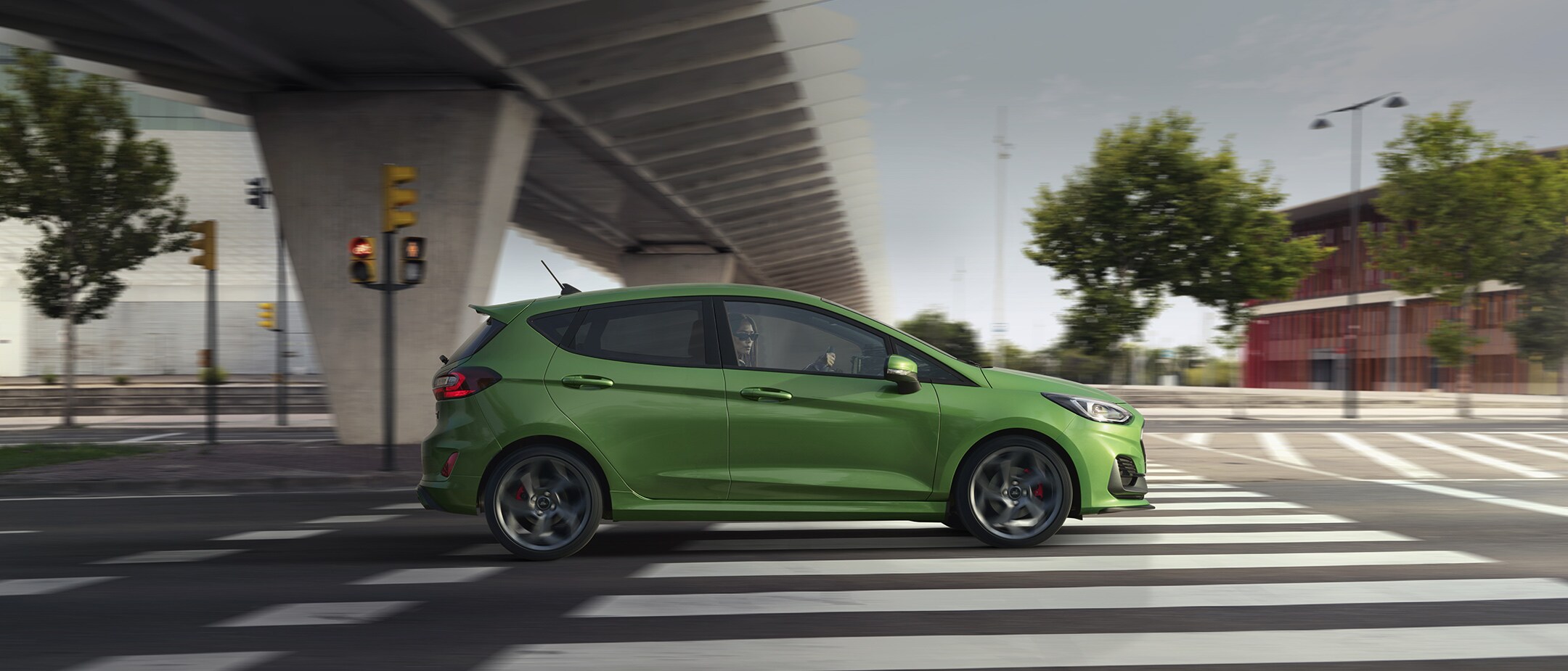 Ford Fiesta ST in Grün. Seitenansicht, unter einer Brücke fahrend.