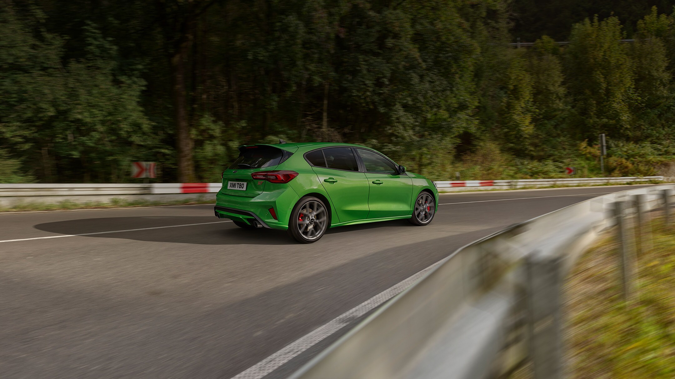 Ford Focus ST in Grün. Dreiviertel-Rückansicht, auf einer Strasse fahrend.