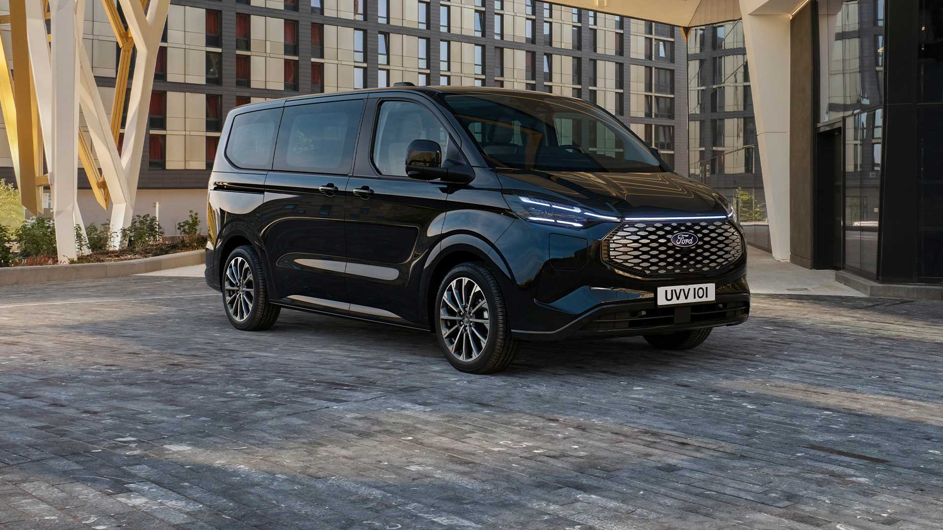 Schwarzer Ford E-Tourneo Custom vor modernem Gebäude geparkt