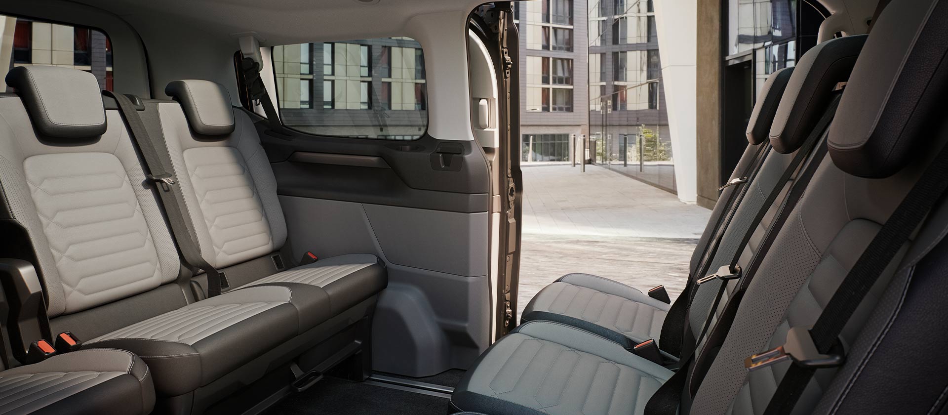 Innenansicht des Ford Tourneo Custom mit mehreren grauen Sitzreihen und Panoramadach