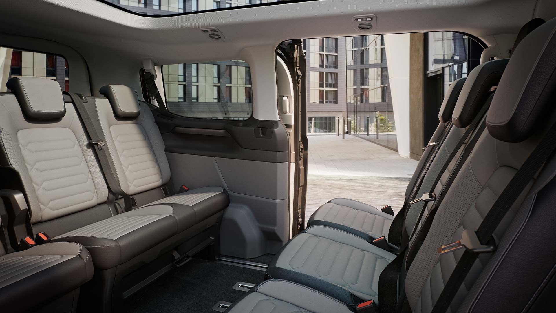 Innenansicht des Ford Tourneo Custom mit mehreren grauen Sitzreihen und Panoramadach