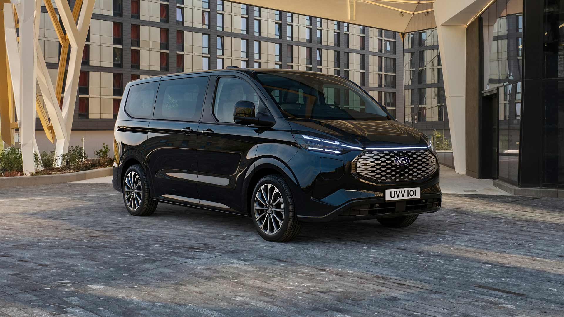 Schwarzer Ford E-Tourneo Custom vor modernem Gebäude geparkt