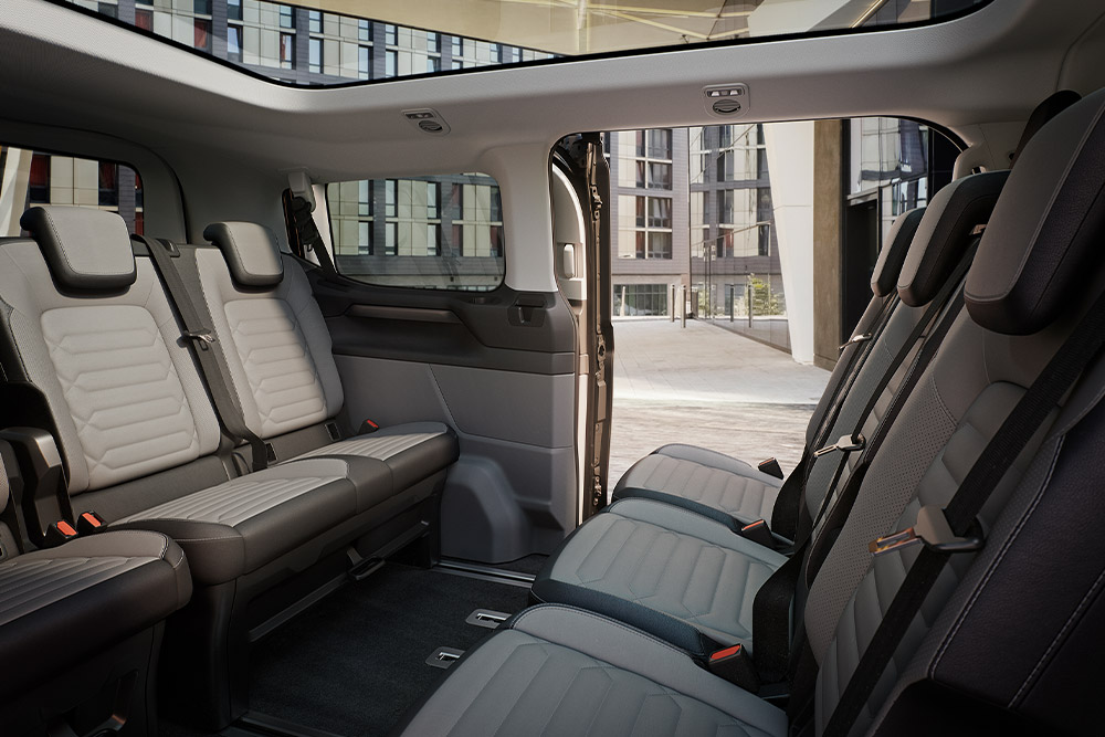 Innenansicht Ford Tourneo Custom mit mehreren grauen Sitzreihen und Panoramadach