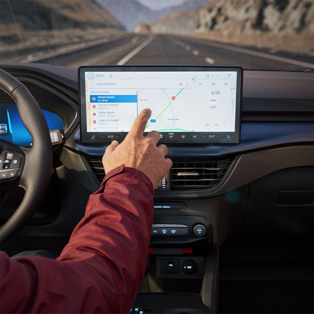 Ein Fahrer nutzt die Vernetzte Navigation auf dem digitalen Bildschirm eines Ford Kuga BlueCruise Edition.