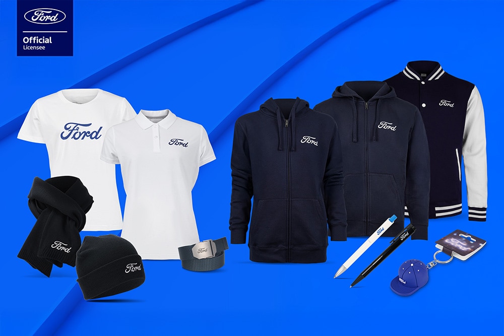 Ford Merchandise-Kollektion mit verschiedenen Ford-Fahrzeugen im Hintergrund sowie Regenschirm, Tassen und Kleidungsstücken im Ford-Design.