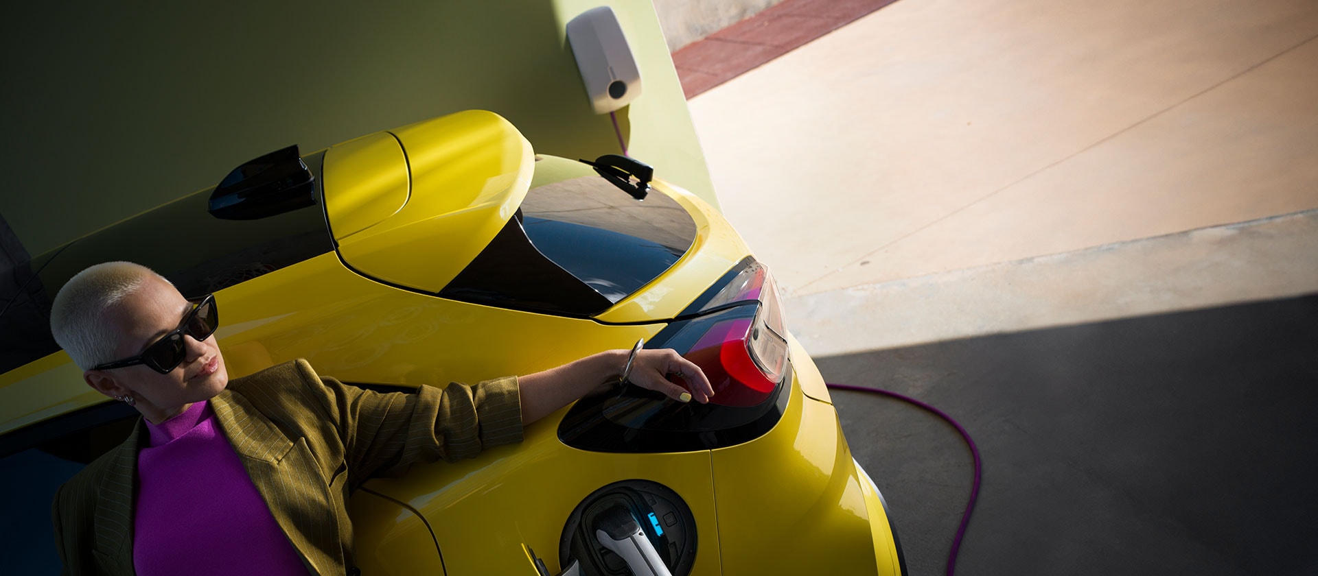 Nahaufnahme des Hecks eines vollelektrischen Ford Puma Gen-E® in Gelb, der an eine Wallbox angeschlossen ist.