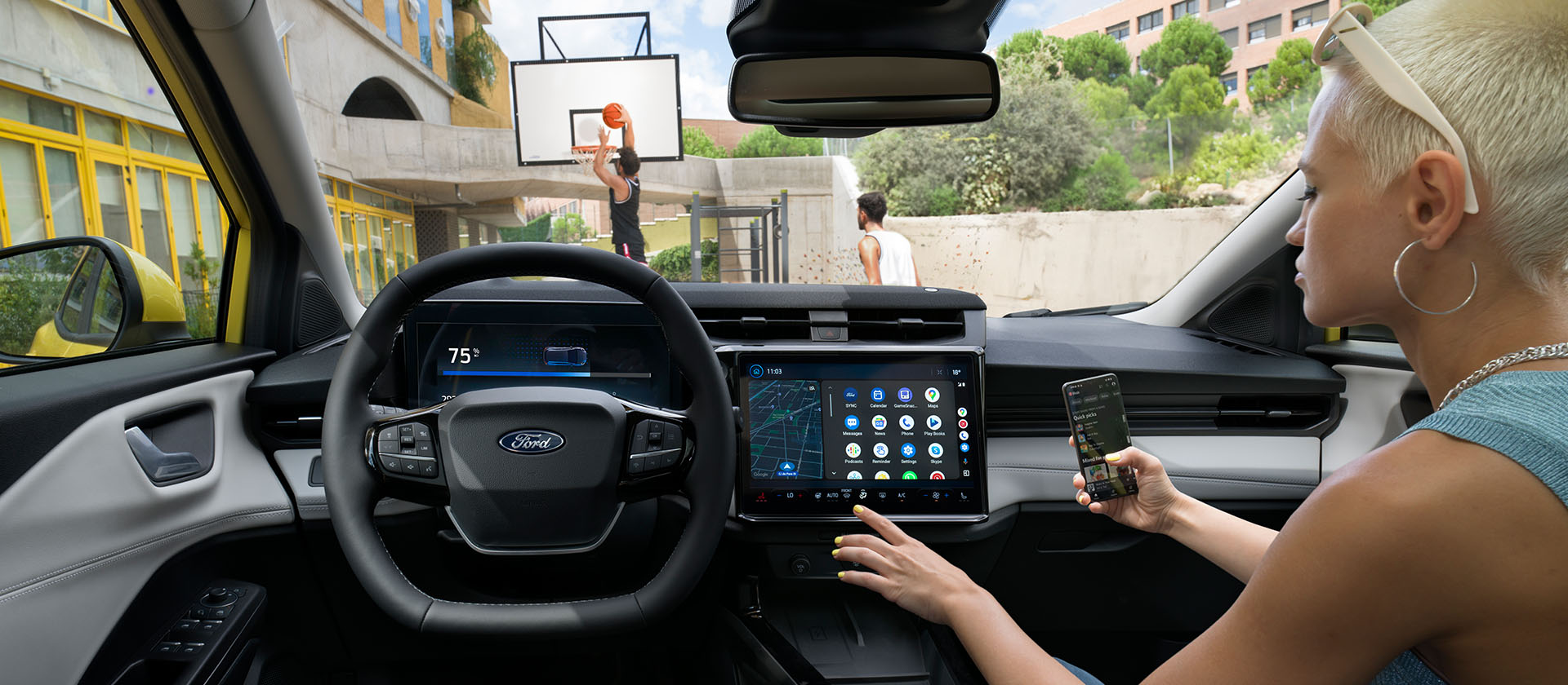 Innenraum des vollelektrischen Ford Puma Gen-E ®, während jemand ein Mobiltelefon kabellos mit dem Touchscreen synchronisiert.