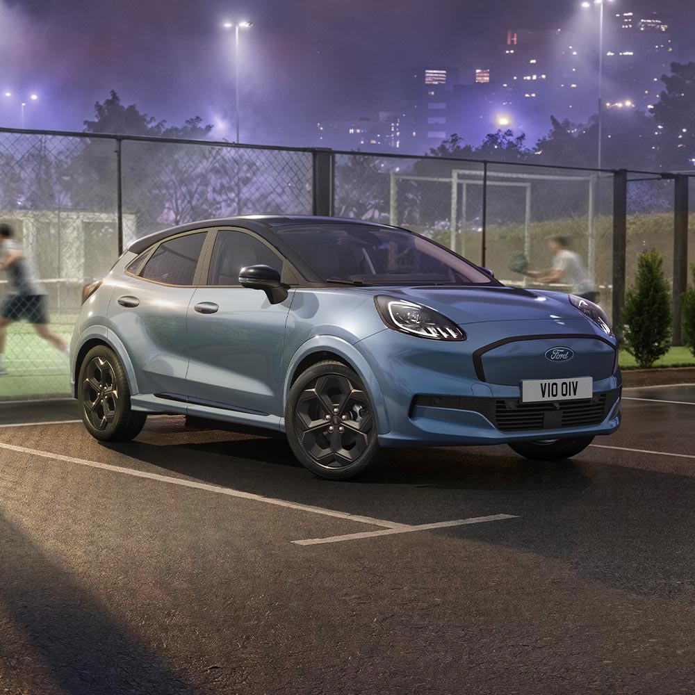 Ein in limitierter Auflage erhältlicher Ford Puma Gen-E in der Farbe Vapour Blue mit BlueCruise-Technologie, der neben einem Padel-Platz im Freien geparkt ist.