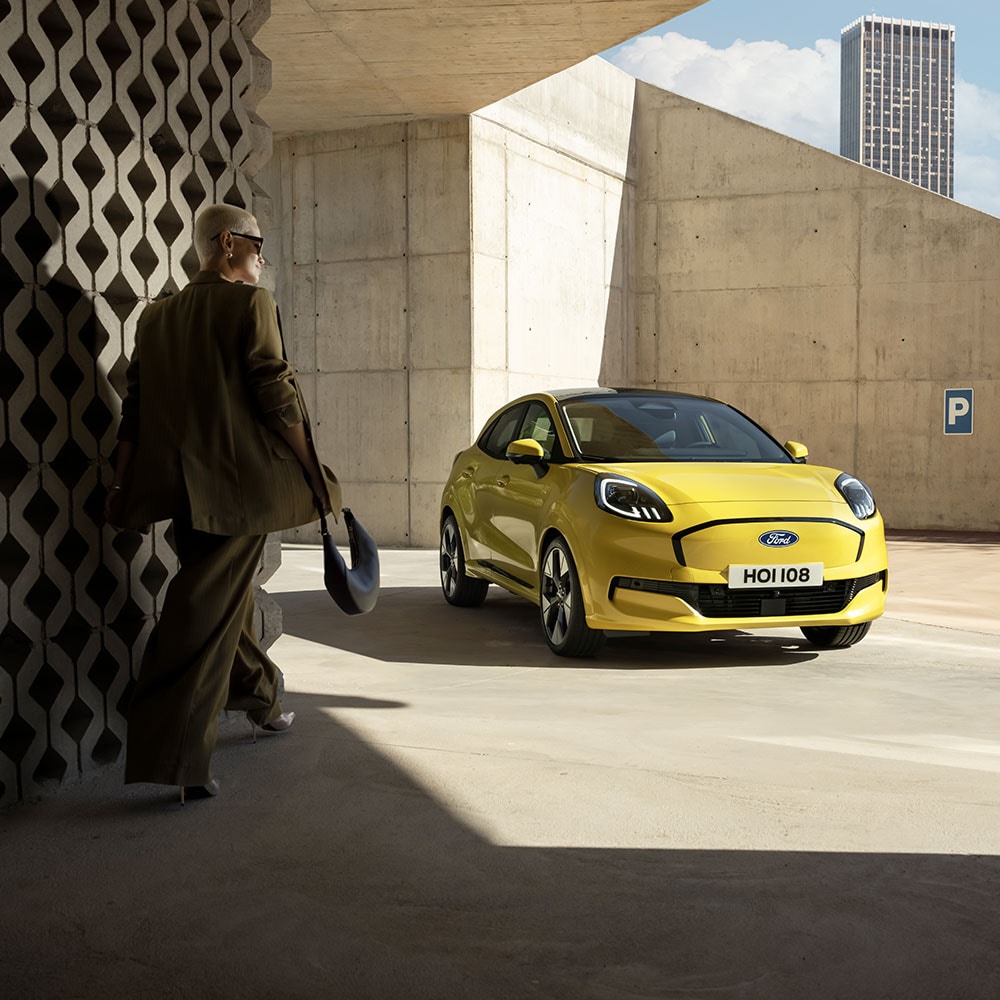 Eine Person geht auf den vollelektrischen Ford Puma Gen-E® in Gelb zu.