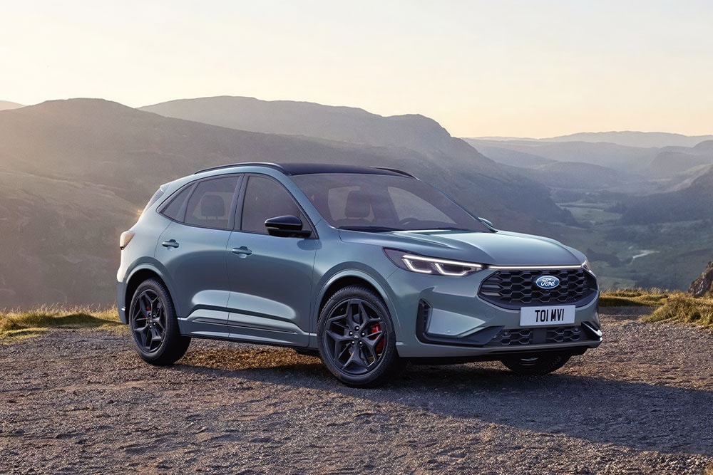 Ein grauer Ford Kuga parkt bei Sonnenuntergang auf einer Schotterstrasse.