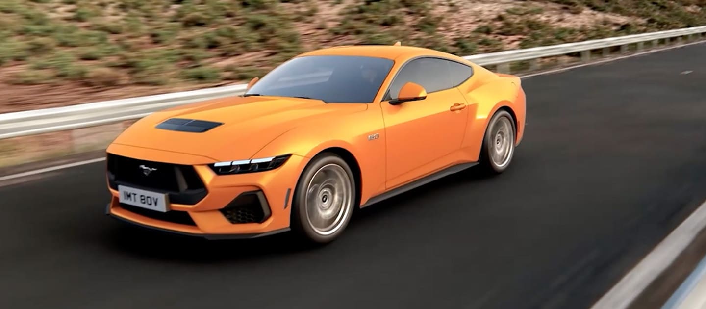 Ford Mustang GT Fastback in Orange Fury fährt auf einer Bergstraße
