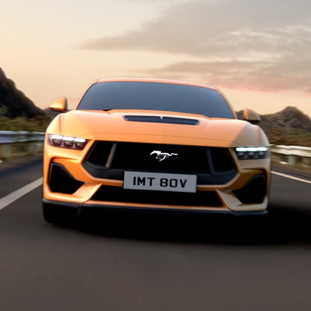 Vorderansicht eines orangefarbenen Ford Mustang mit Nahaufnahme der Scheinwerfer, des Kühlergrills und des Mustang-Emblems