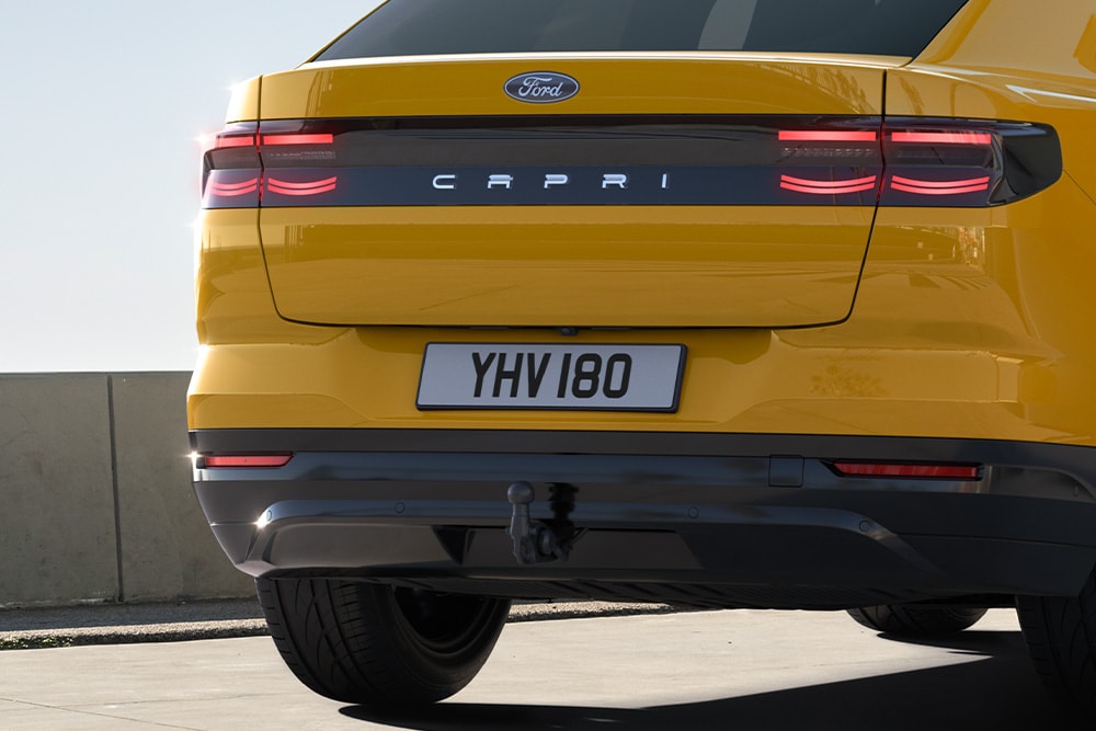 Rückansicht eines gelben Ford Capri®, der auf einer Stadtstrasse fährt.