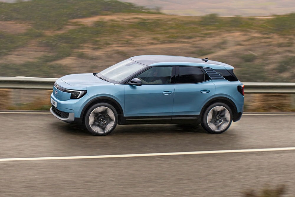 Ein blauer Ford Explorer, der eine Bergstrasse entlangfährt, mit dem Fünf-Sterne-Logo 2024 von Euro-NCAP in der oberen linken Ecke.