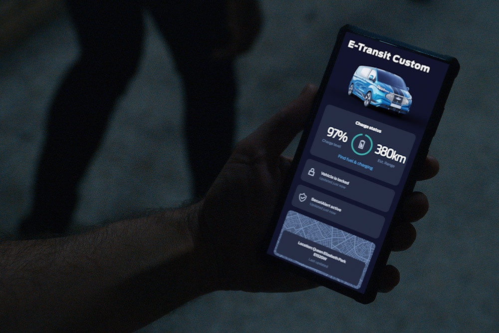 Smartphone zeigt E-Transit Custom in der FordPass App mit Lade- und Standortstatus