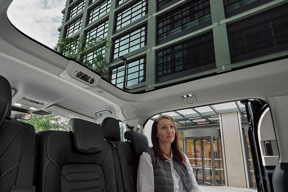 Person, die nach oben zum Panoramadach des brandneuen Tourneo Custom schaut