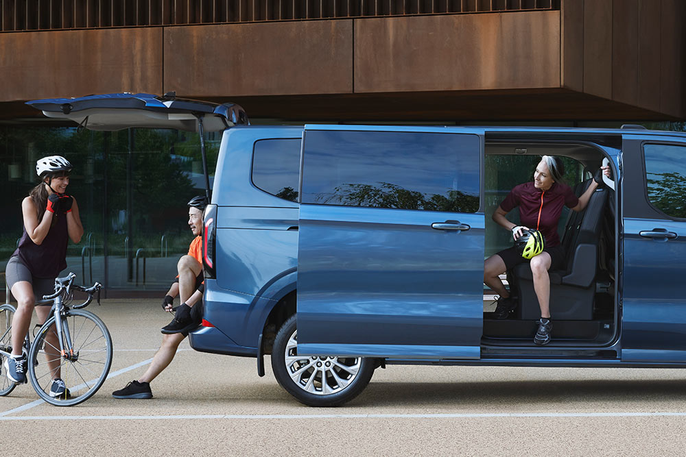 Seitenansicht des brandneuen Tourneo Custom mit Personen drumherum