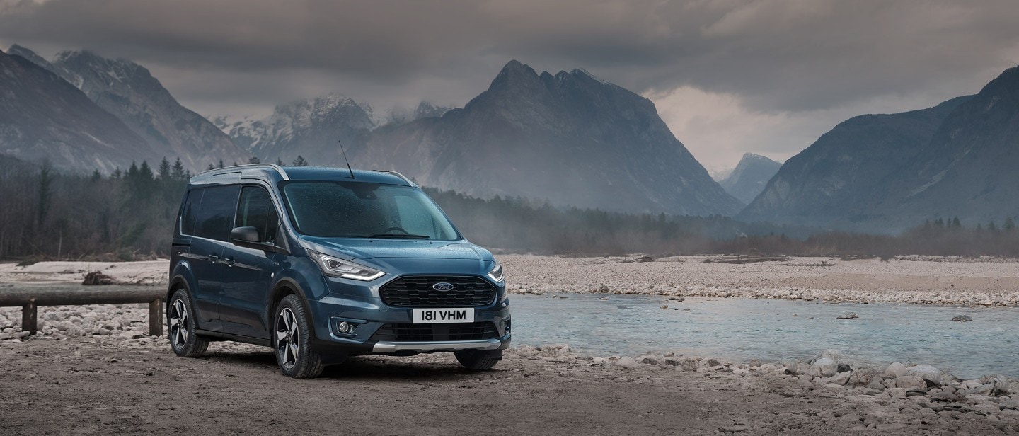 Blue Ford Transit Connect driving in city