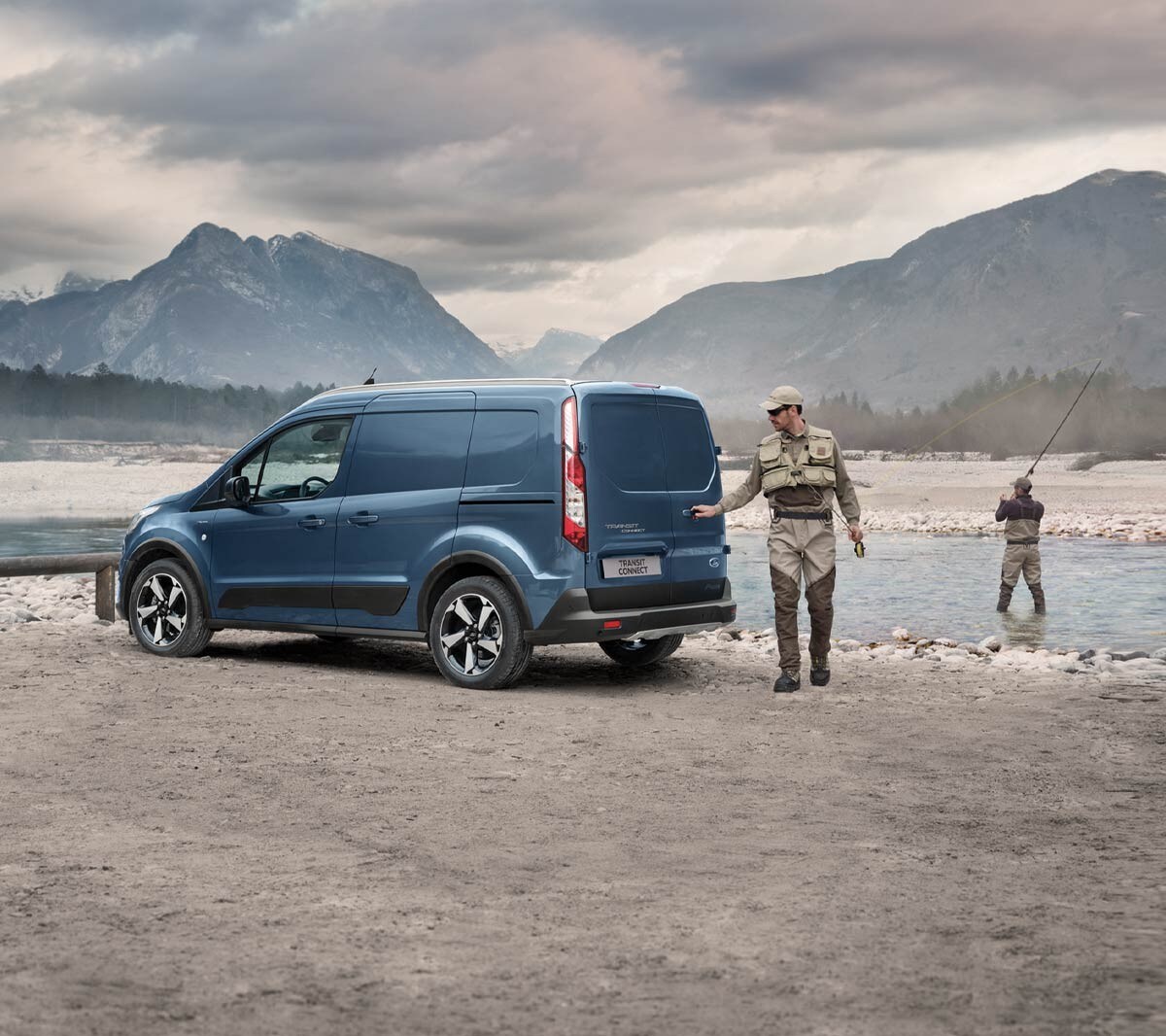 Ford Transit Connect in Blau ¾-Heckansicht parkt an Gewässerufer im Gebirge mit Angler, der Hecktür öffnet