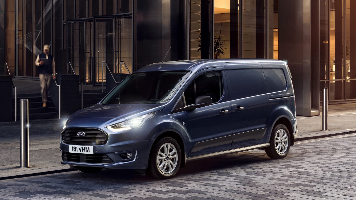 Ford Transit Connect Blau ¾-Frontansicht parkt vor mit eingeschalteten Scheinwerfern