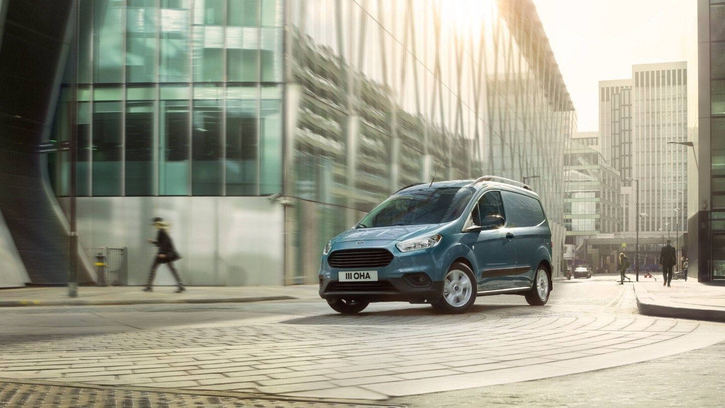 Ford Transit Courier in Grau ¾-Frontansicht fährt durch enge Strassen in der Innenstadt