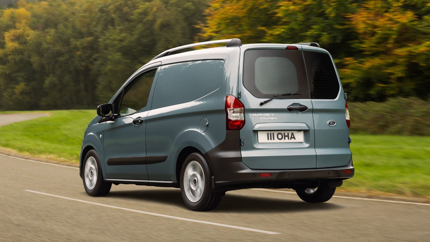 Ford Transit Courier in Grau ¾-Heckansicht fährt auf Landstrasse