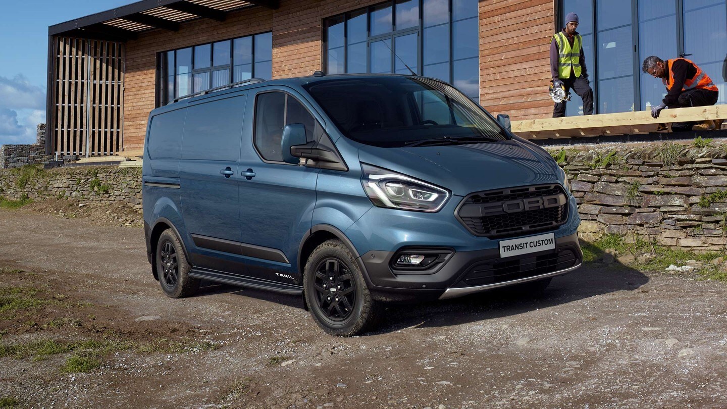 Ford Transit Custom Kastenwagen Trail Blau ¾-Seitenansicht parkt auf Baustellenstrasse vor Gebäude