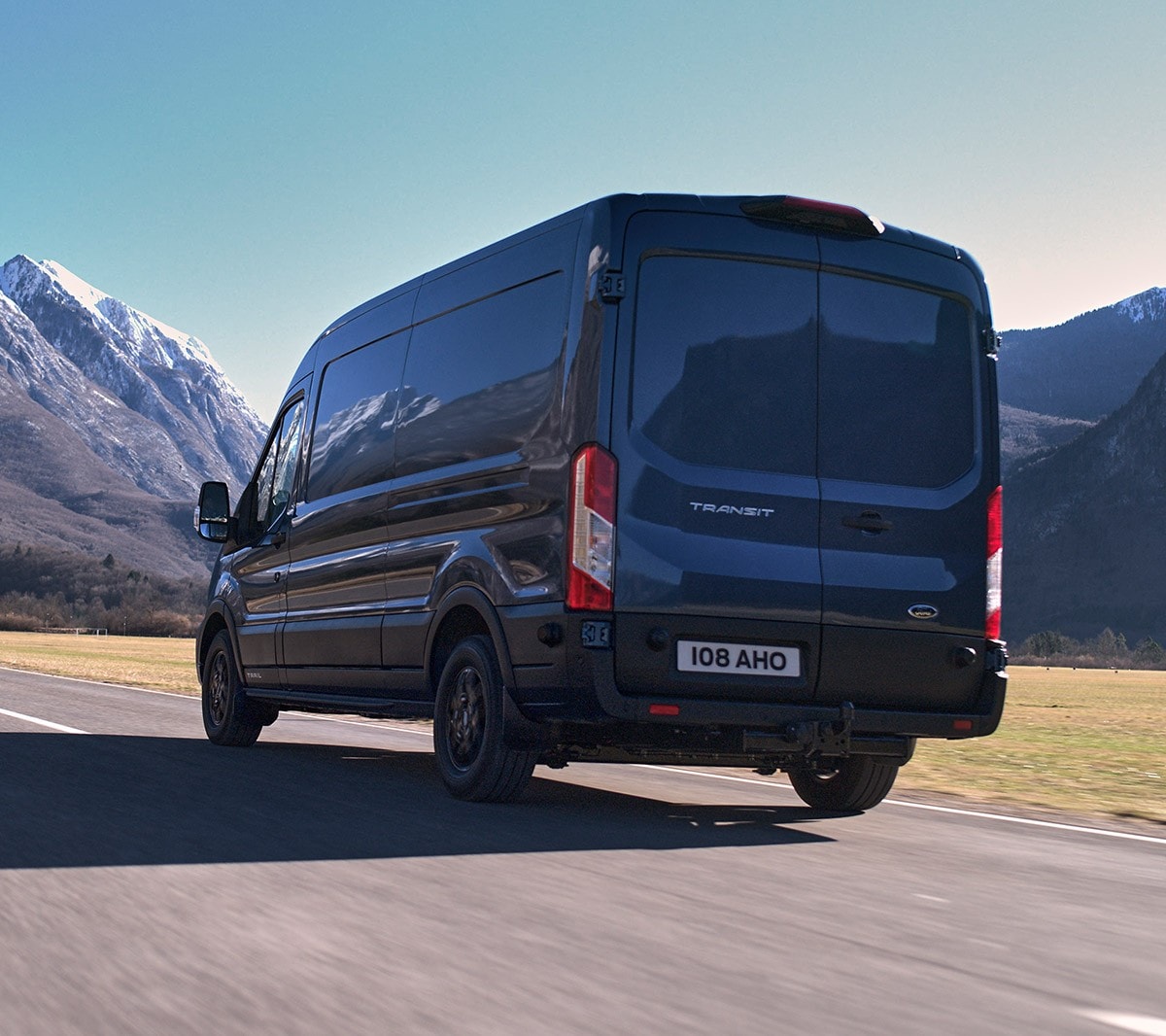 Ford Transit Kastenwagen Blau ¾-Heckansicht fährt über Land