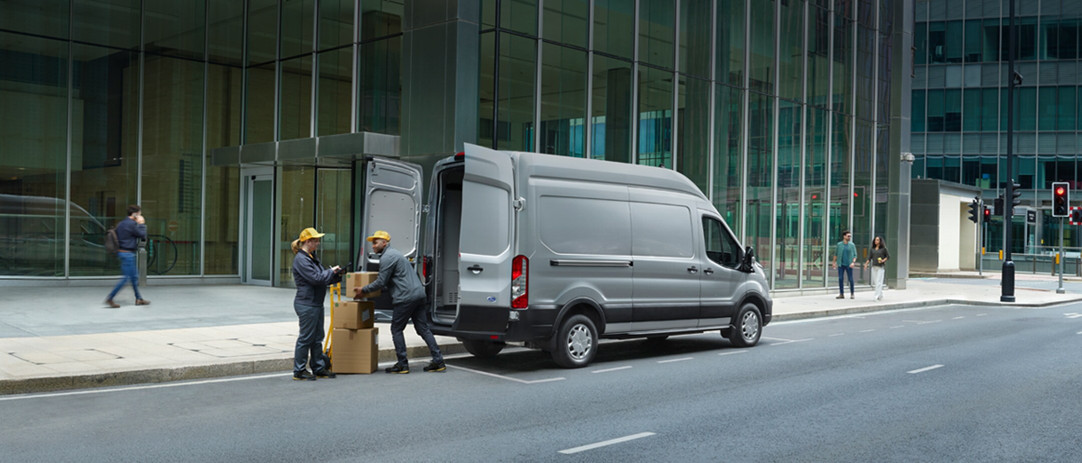 New Ford E-Transit with delivery men loading up boxes in 3/4 back view