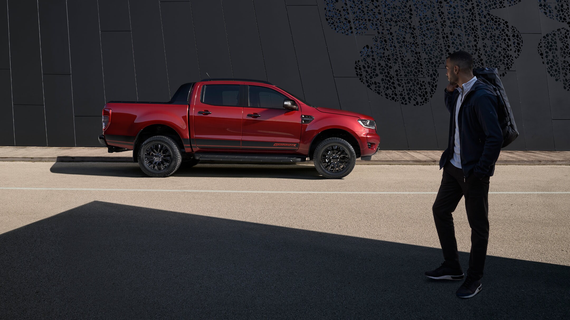 Ford Ranger Stormtrak rot Seitenansicht parkend und Mann im Vordergrund