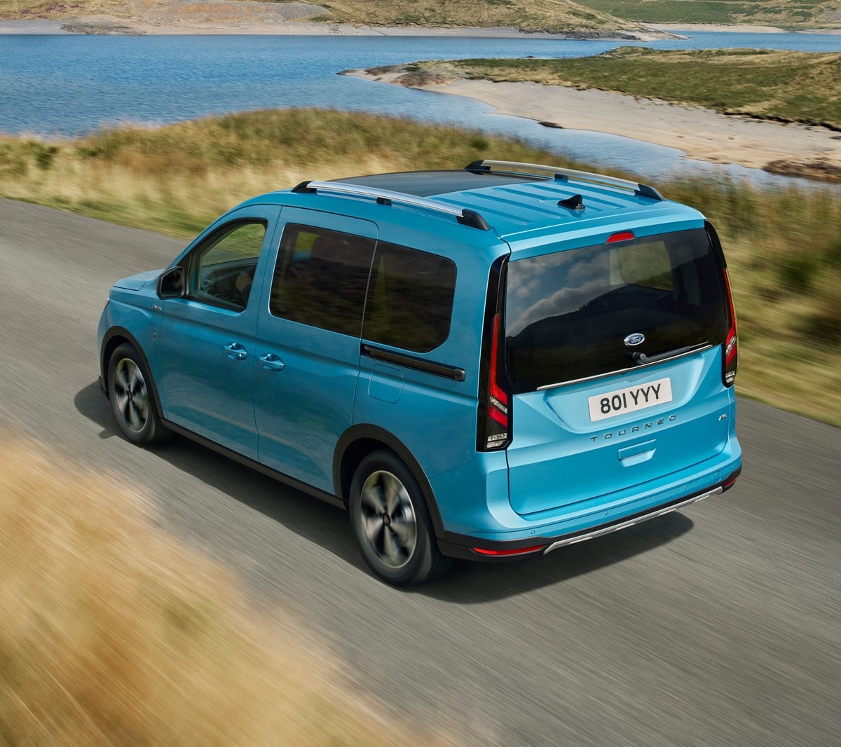 Ford Tourneo Connect in Hellblau ¾-Heckansicht fährt auf Landstrasse