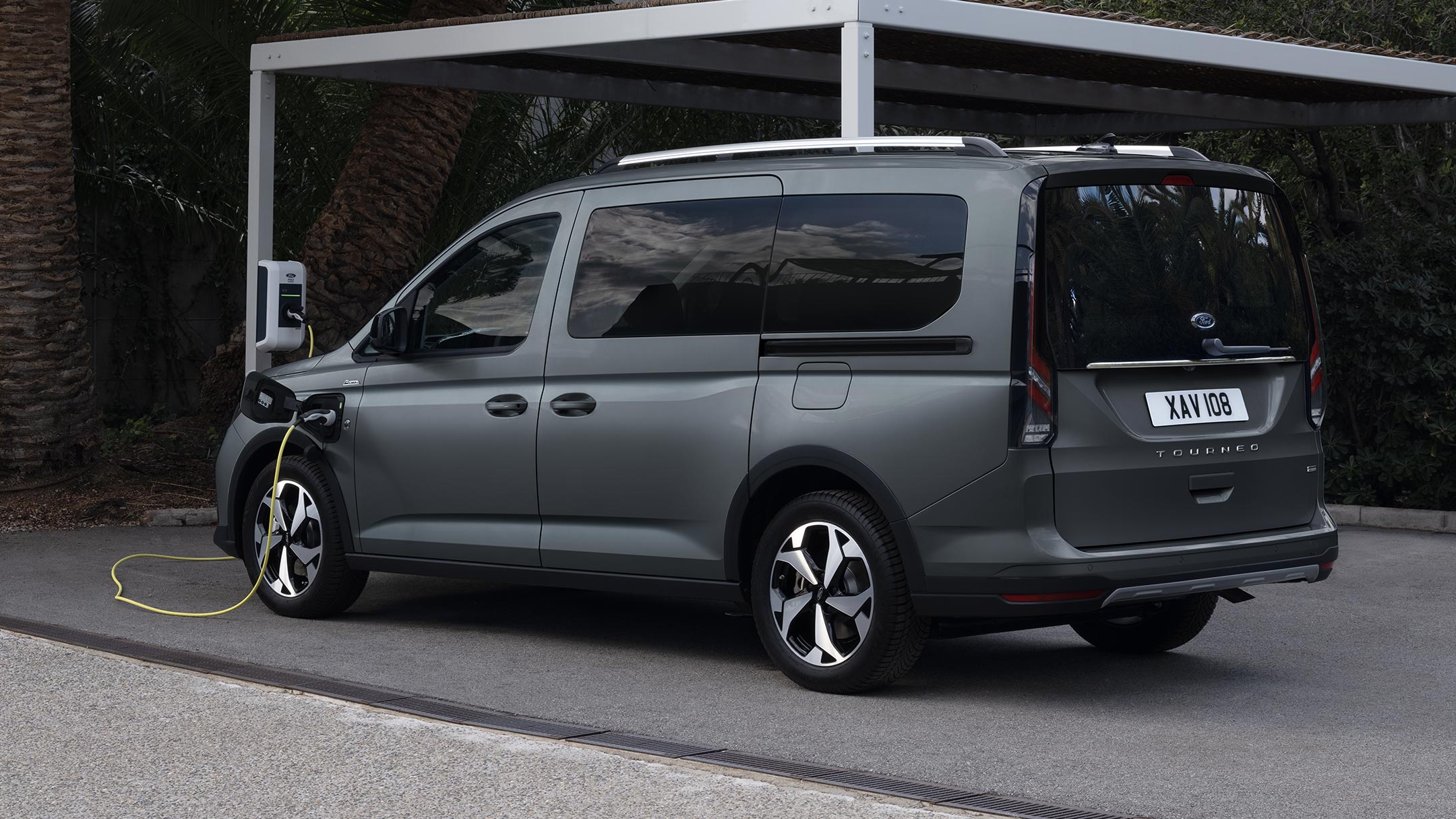 Ford Tourneo Connect in Grau ¾-Frontansicht parkt vor gebirgiger Landschaft mit Fluss im Hintergrund