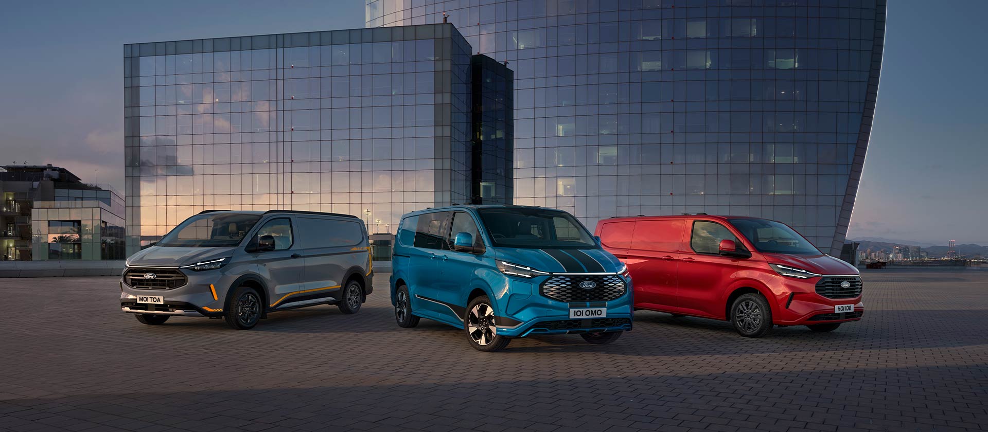 Drei geparkte Ford Transit Custom Sport Transporter in Grau, Blau und Rot.