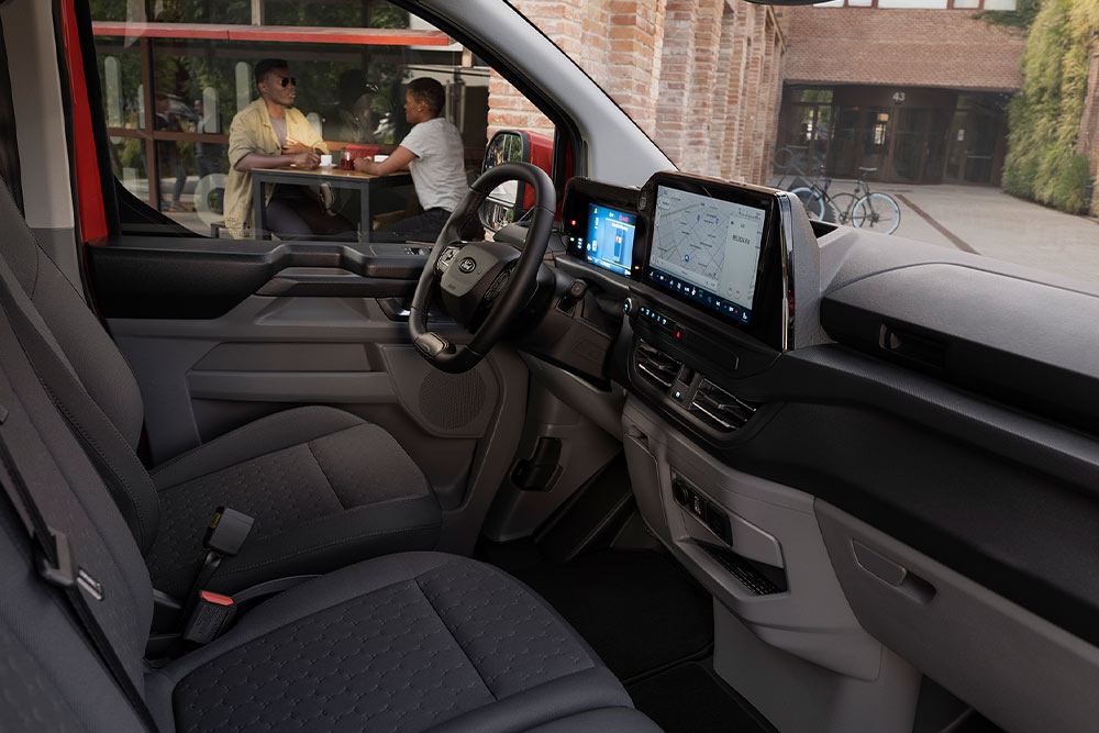 Person sitzt auf dem Fahrersitz eines roten Ford Transit Custom