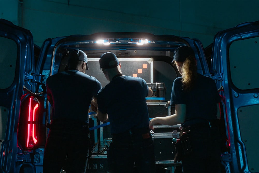 Drei Personen arbeiten im hinteren Bereich eines Ford Transit Custom. 
