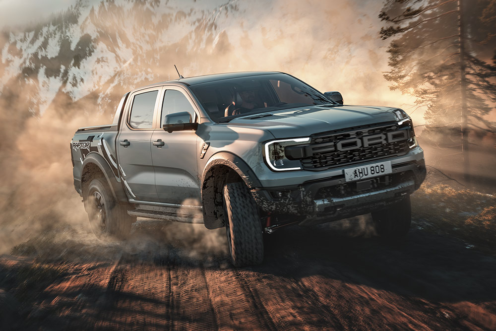 Ein Ford Ranger Raptor fährt im Baja-Modus auf einem Feldweg, im Hintergrund eine Berglandschaft.