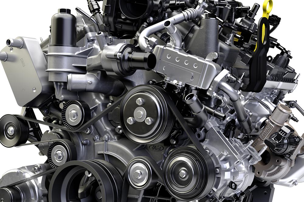 Nahaufnahme eines Fahrzeugmotors. Man sieht mehrere Riemen, Riemenscheiben und mechanische Komponenten.
