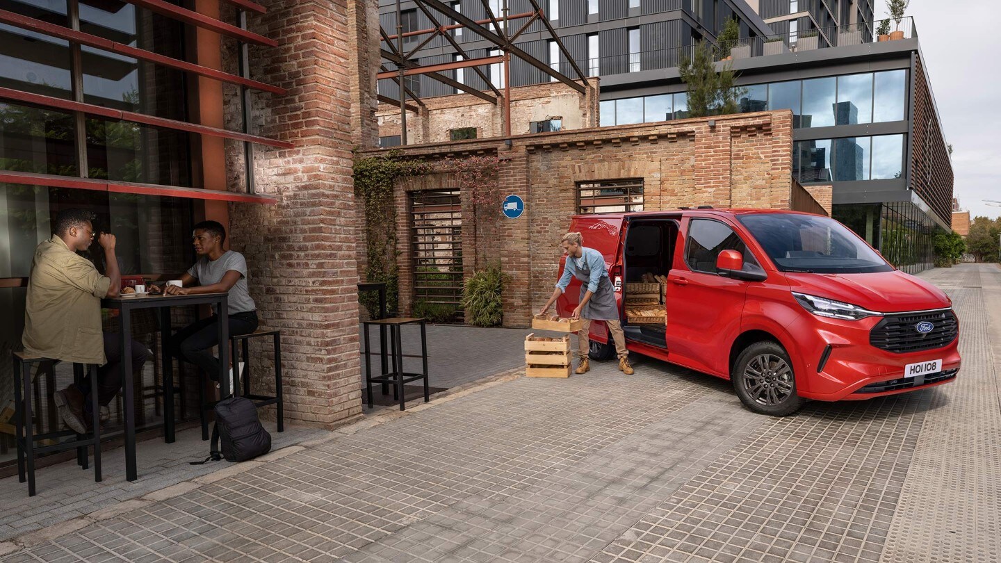 Ford Transit Custom in Rot in der ¾-Frontansicht wird vor Restaurant entladen