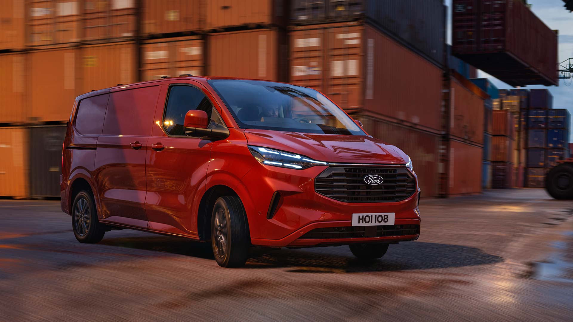 Roter Ford Transit Custom Kleintransporter fährt durch einen Hafenbereich