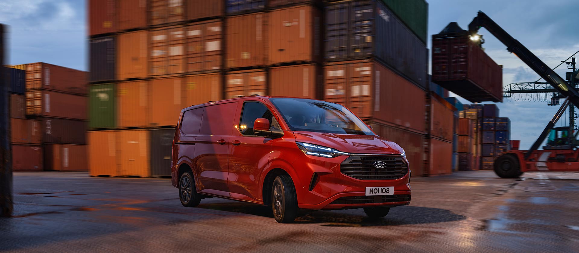 Roter Ford Transit Custom Kleintransporter fährt durch einen Hafenbereich