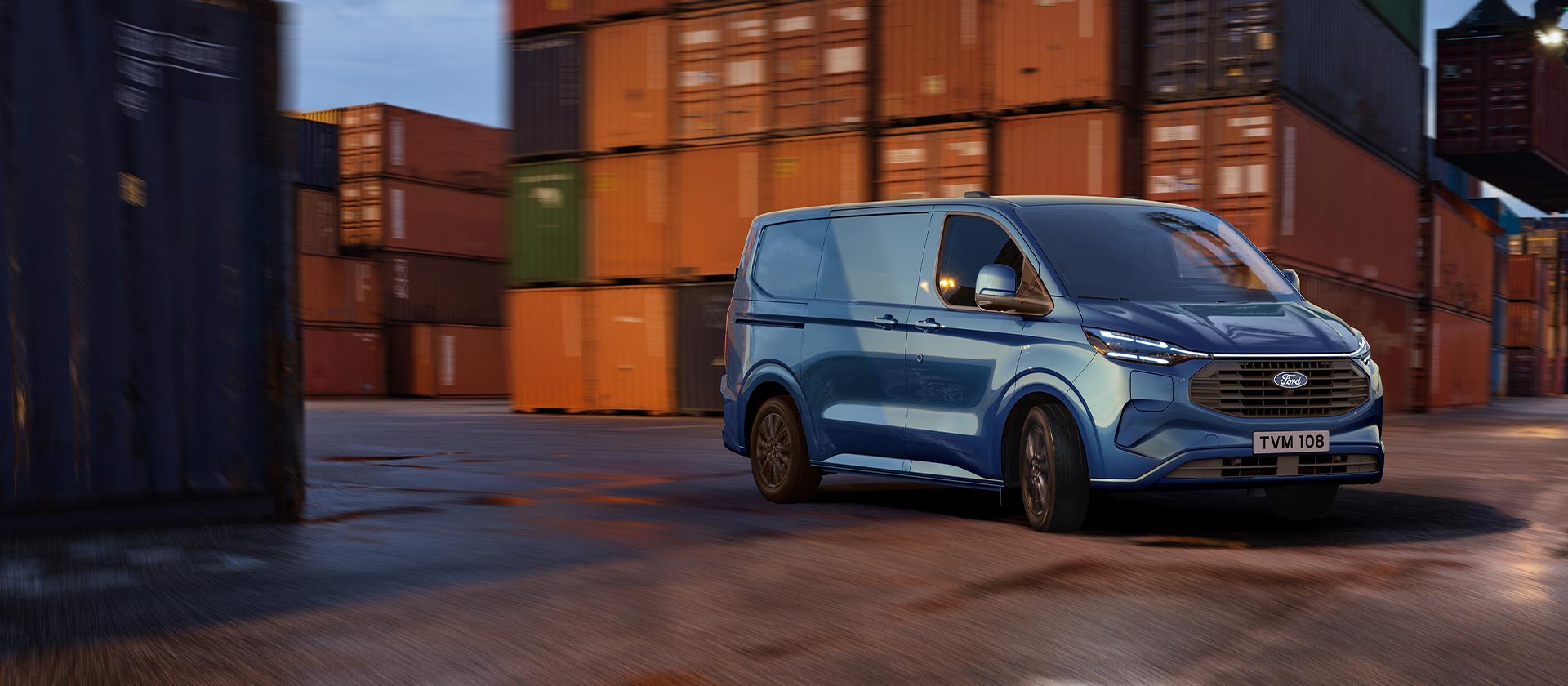 Blauer Ford Transit Custom Kleintransporter fährt durch einen Hafenbereich