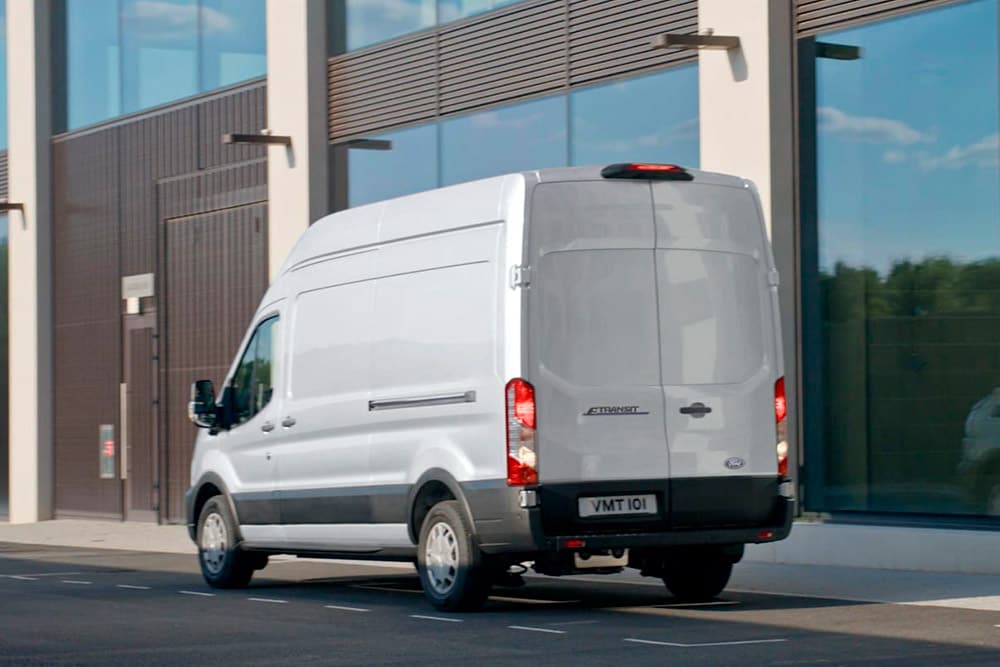 Rückansicht eines weissen Ford Transit Van, der auf einer Strasse geparkt ist.