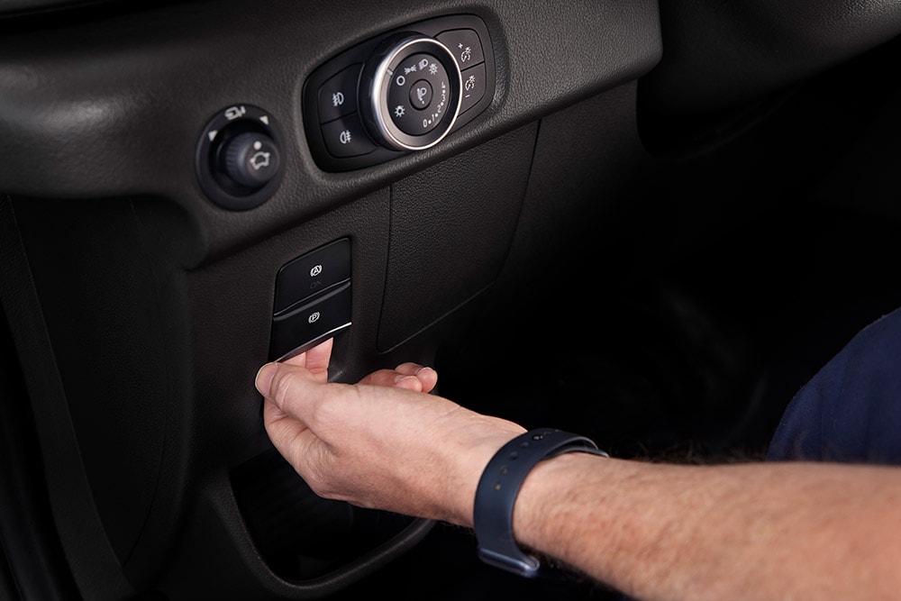 Nahaufnahme einer Hand, die einen Knopf auf dem Armaturenbrett eines Ford E-Transit Elektro-Van drückt.