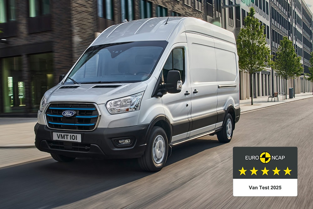 Silberner Ford E-Transit Elektro-Van,  der auf einer Strasse fährt, mit dem Abzeichen "Gold 2022 Commercial Van Safety".