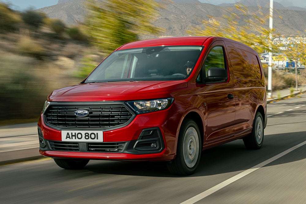 Ein Ford Transit Connect fährt auf einer Strasse und zeigt den Kühlergrill und die automatischen Scheinwerfer.