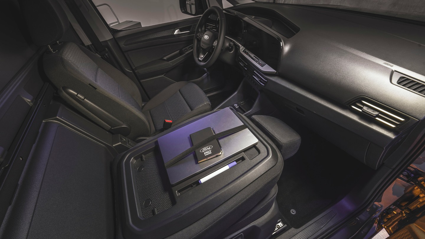 Auf dem Arbeitstisch des Ford Transit Connect liegen ein Laptop und ein Ford Pro Notizbuch.