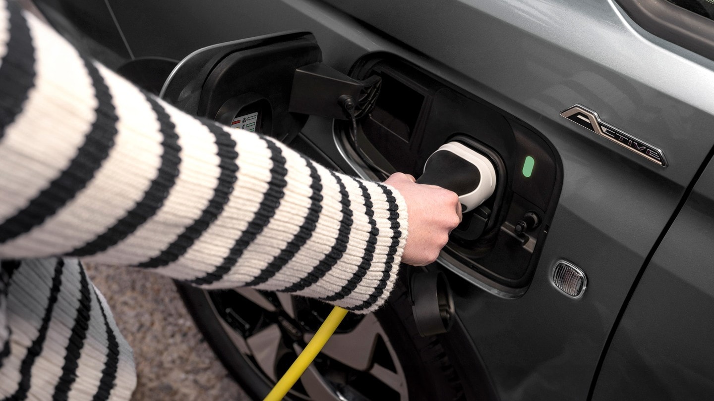 Ein Ladekabel ist in die Ladebuchse des Ford Transit Connect in Boundless Blue eingesteckt.